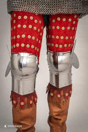 Armadura de piernas medieval en acero y piel roja
